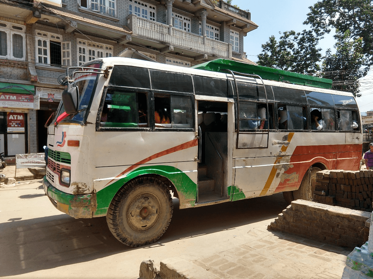 Local bus on the Bhaktapur–Nagarkot road — white, green and orange stripes, roof rack
